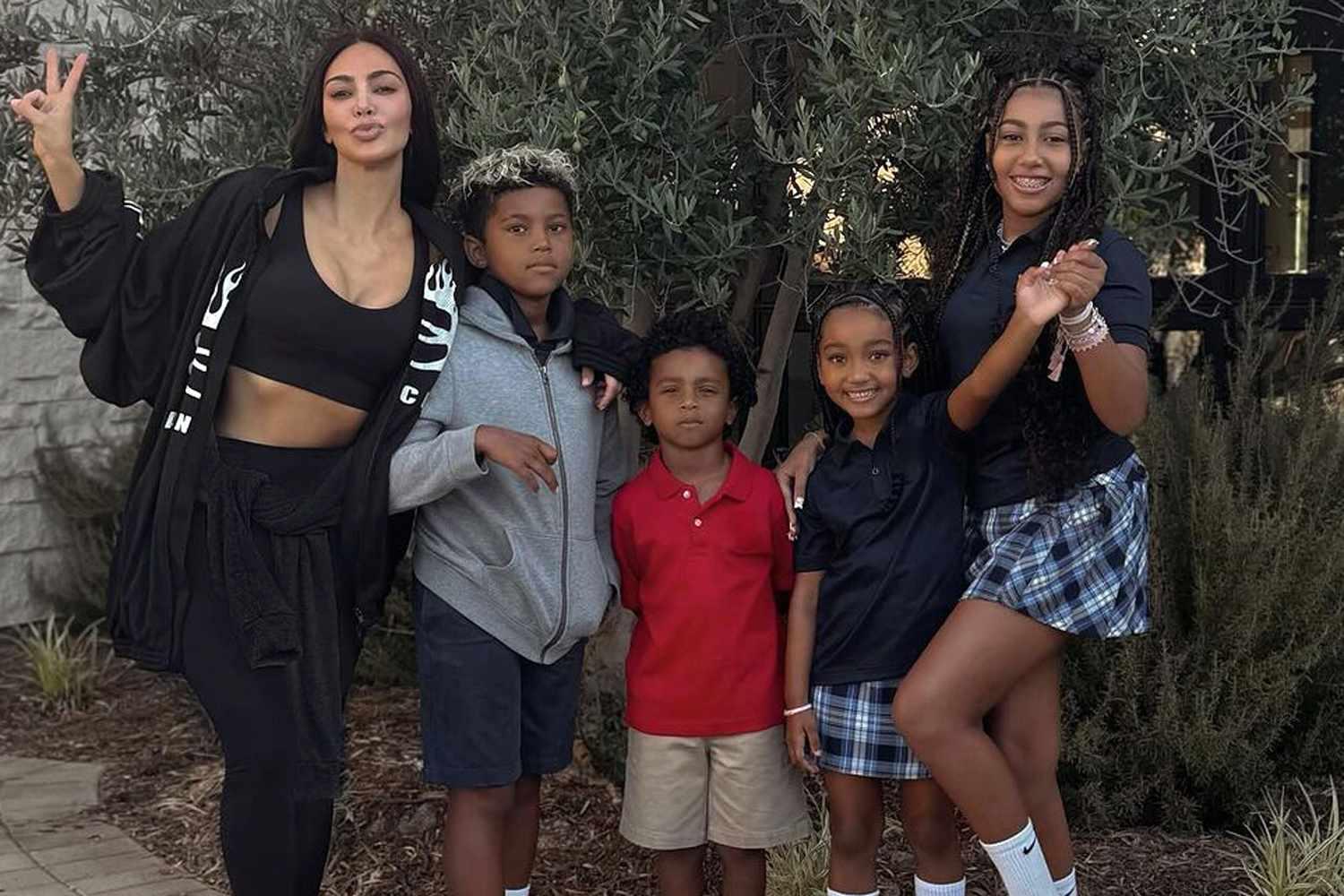 Kim Kardashian smiling with her four children in a park setting