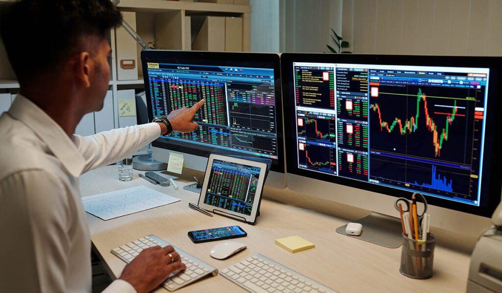 trader analyzing multiple market charts and data on screens